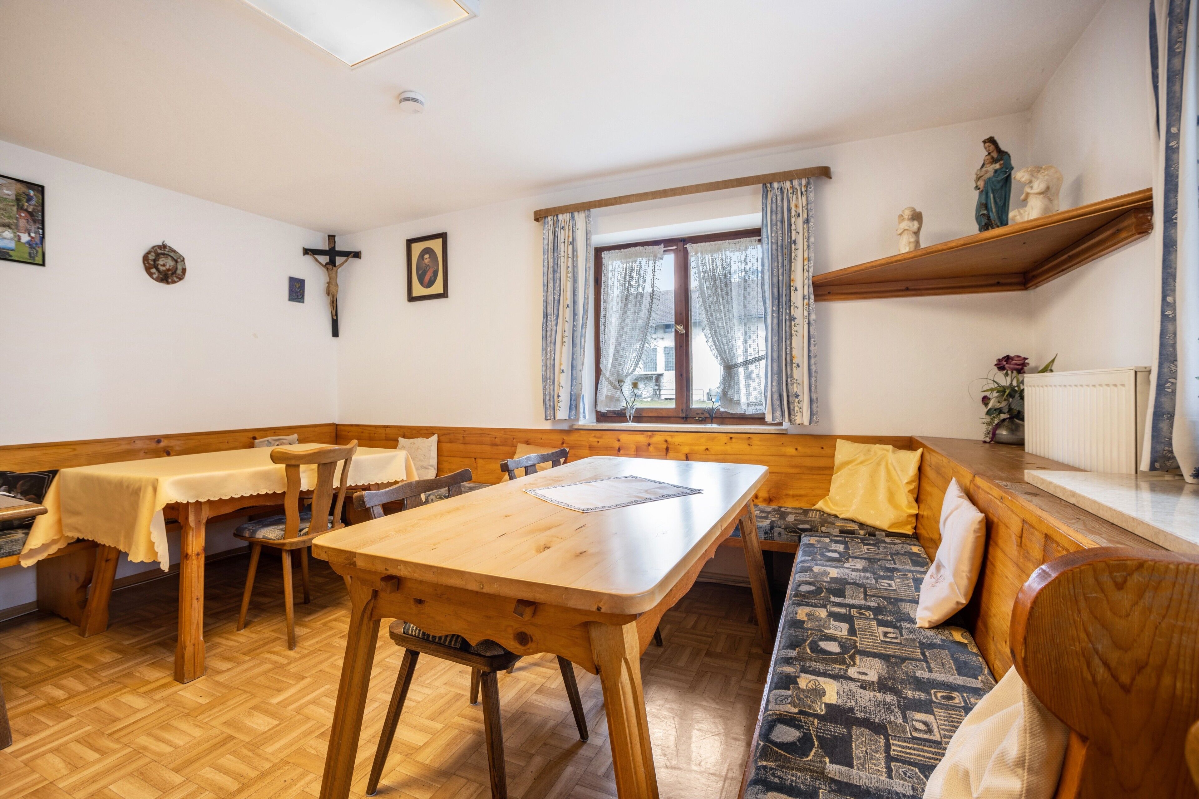 A dining area with wooden furniture, a bench, and a window with curtains.
