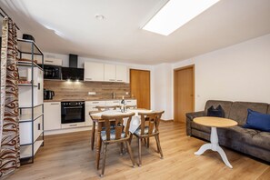 Een moderne keuken met een eettafel en stoelen, een bank en een houten vloer.