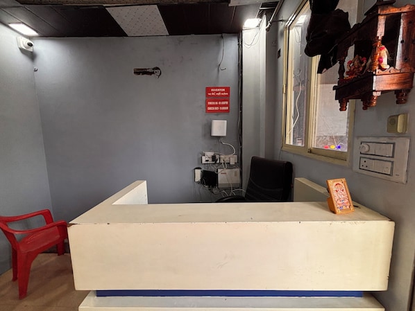 Una recepción con una silla roja, un cartel que indica horarios de registro y una ventana con vistas.