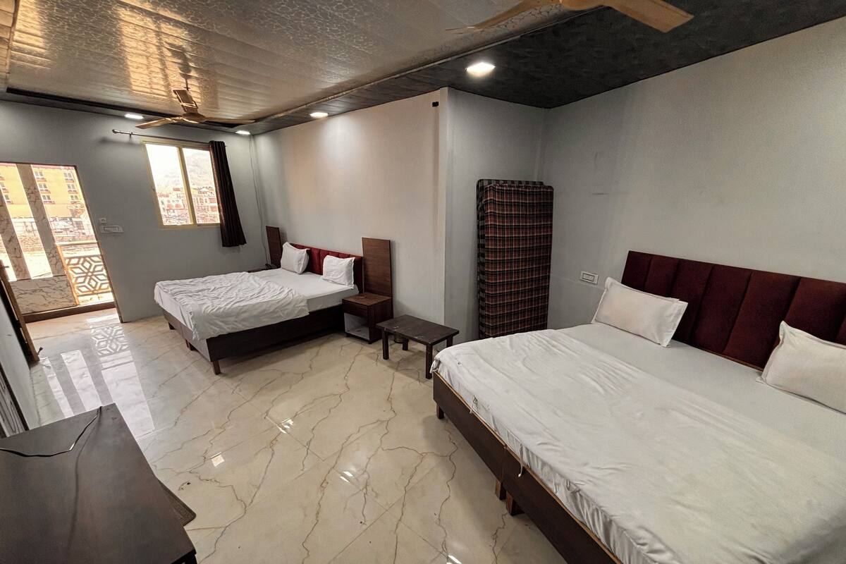 A hotel room with two beds, a desk, and a window.
