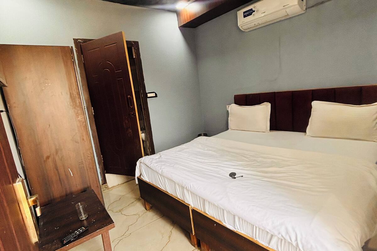 A bedroom with a wooden bed, a ceiling fan, and an air conditioning unit.
