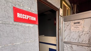 A reception area with a red sign, a marble wall, and a door leading inside. - Dharohar Homestay (Rishikesh)