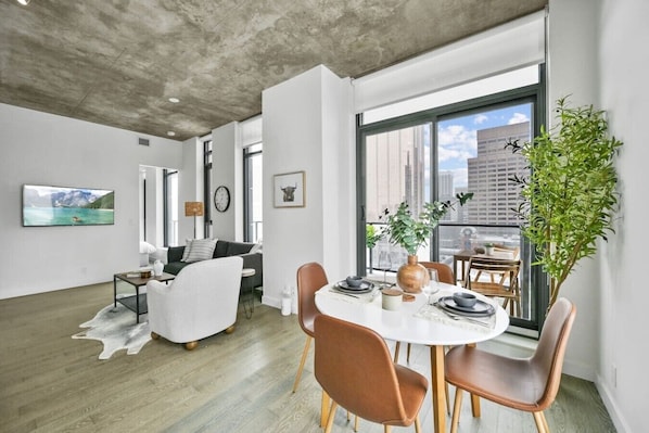 A modern living room with a dining area, large windows, and a view of the city. - Calgary Tower View | King Bed | Mins to Saddledome (Calgary)