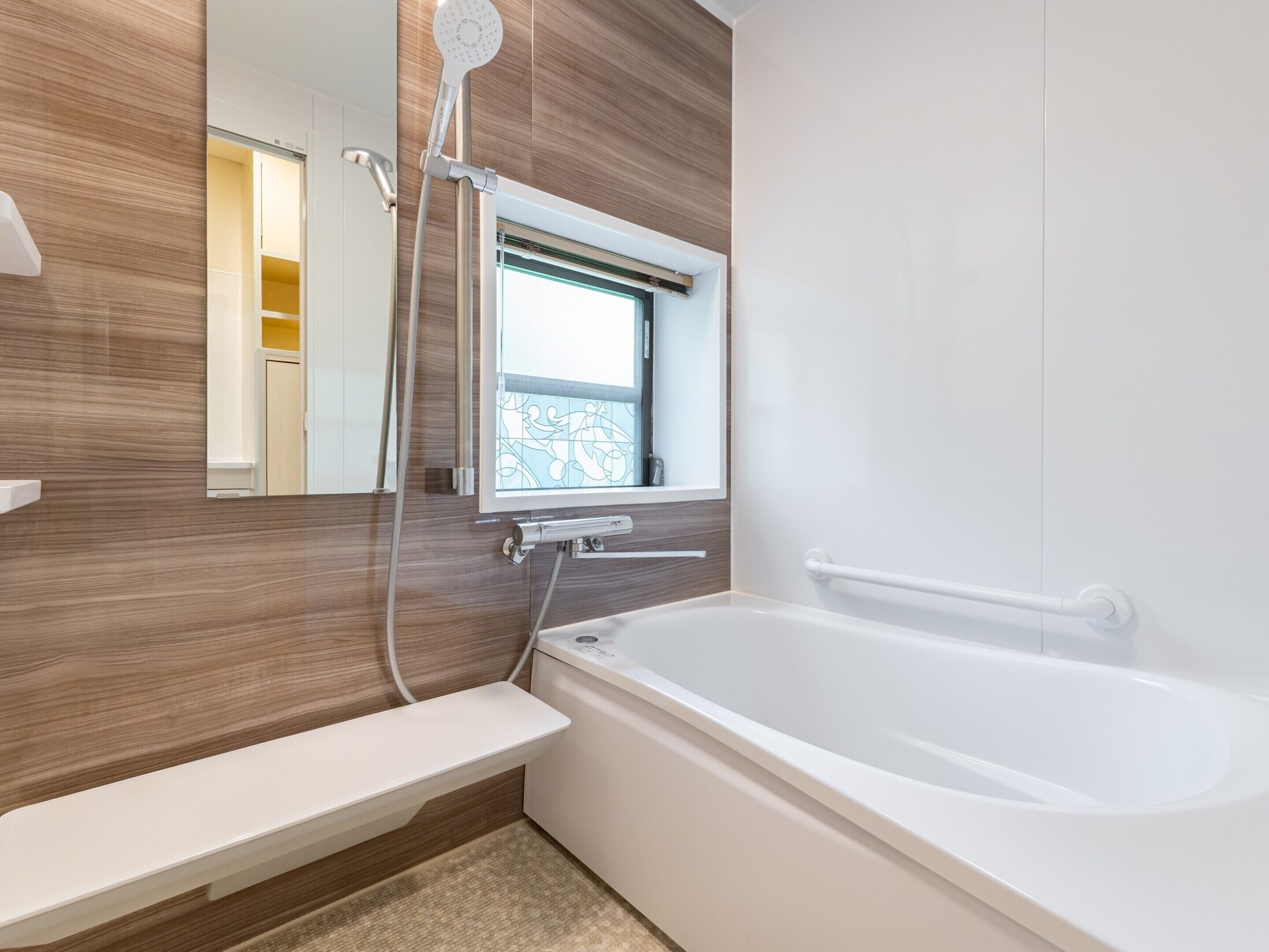 A modern bathroom with a bathtub, a shower, a vanity with a mirror, and a window.