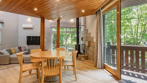 Un intérieur moderne avec un plafond en bois, une table de salle à manger ronde entourée de chaises, un canapé et un téléviseur.