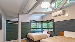 Une chambre avec deux lits, une lucarne et une fenêtre donnant sur les arbres.