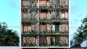 Un immeuble à plusieurs étages doté de balcons, une voiture garée devant, et un ciel dégagé.