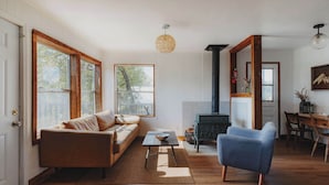 A living room with a sofa, a blue armchair, a coffee table, and a fireplace.