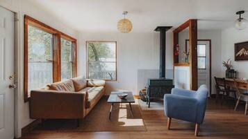 Un salon avec un canapé, un fauteuil bleu, une table basse et une cheminée.