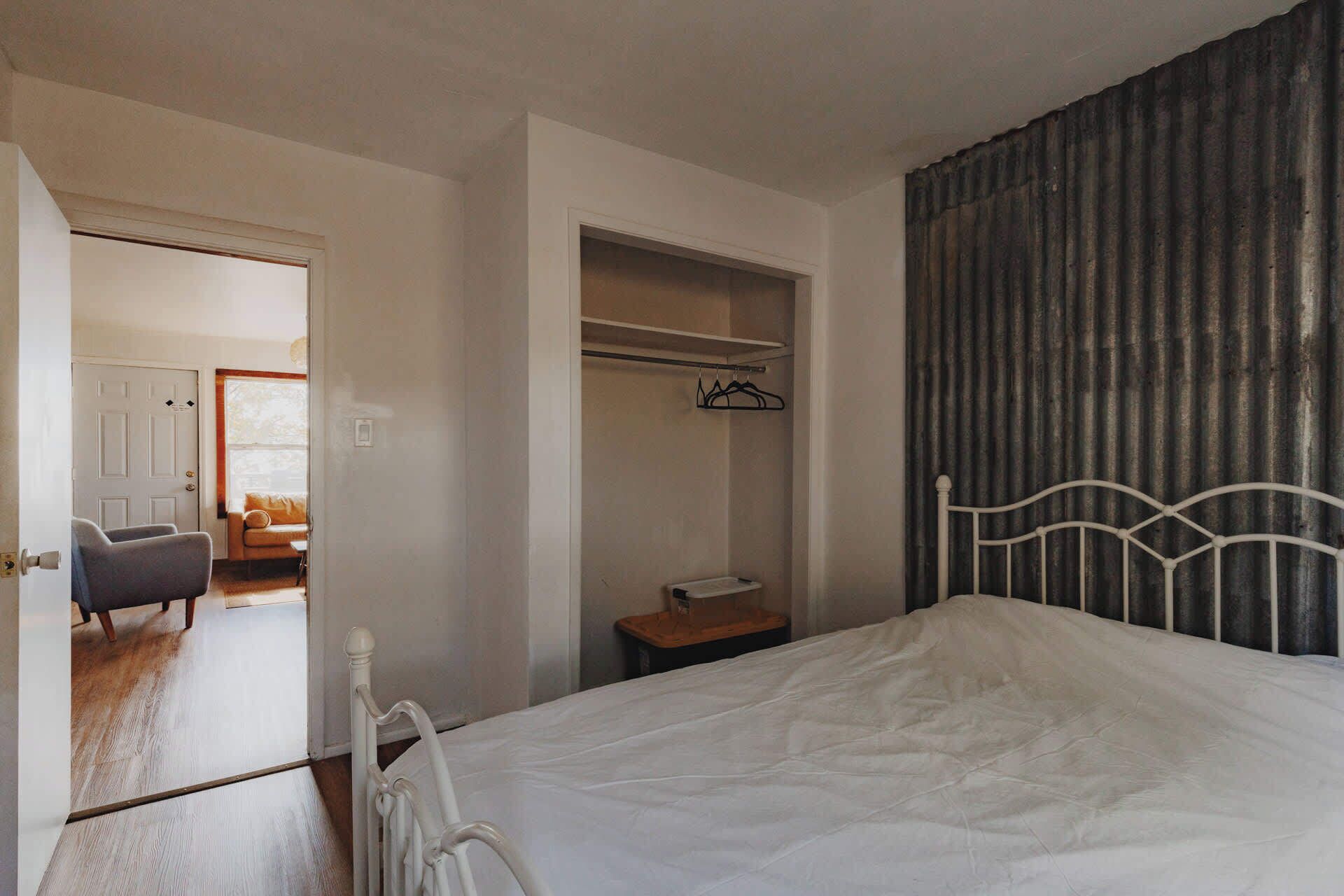Une chambre à coucher avec un lit, une armoire, une petite table et une chaise.