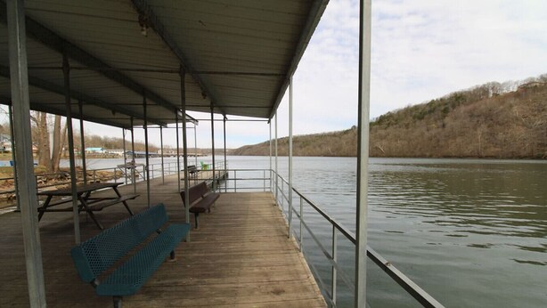 A covered wooden deck with benches and picnic tables overlooking a calm river. - Idlewild at Duck Harbor Resort (Rockaway Beach)