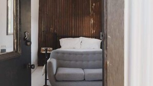 Une chambre à coucher avec un lit, un mur à texture, un luminaire suspendu et un tapis à rayures.