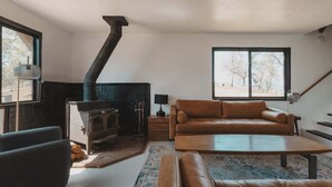 A living room with a fireplace, a sofa, a coffee table, and a lamp. - Event venue in nature retreat (Dunlap)