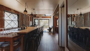 A modern kitchen with a long island, bar stools, and pendant lighting. - Secluded rustic 3-bedroom cabin on private land (Dunlap)