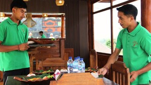 A restaurant with wooden furniture and a view of buildings outside. - Munduk Luwih Ecolodge Bedugul by AGATA (Baturiti)