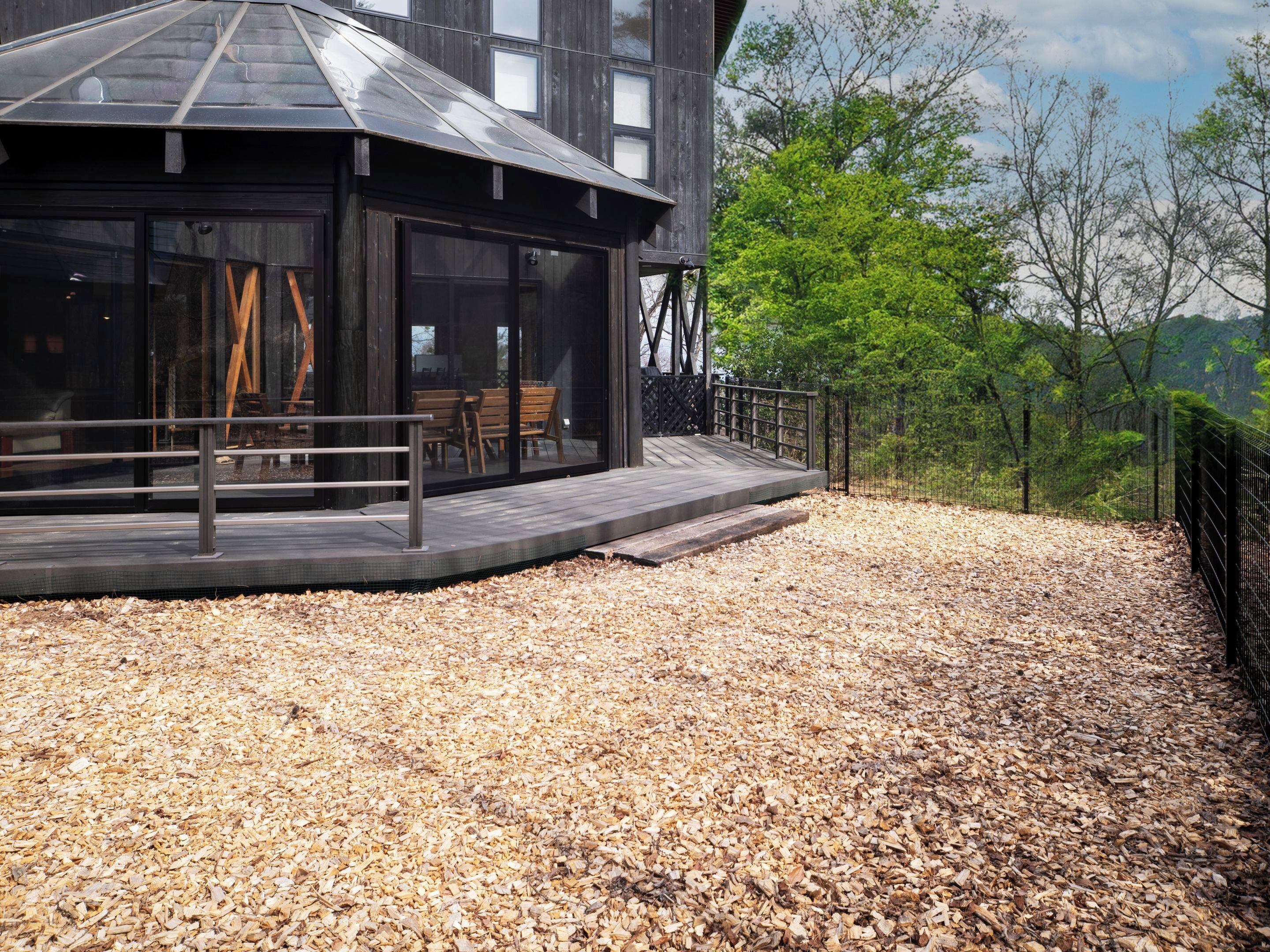 Un bâtiment moderne doté d’une terrasse en bois, de grandes fenêtres et d’une rambarde en métal.
