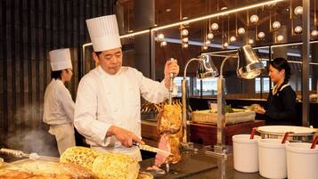 Un chef preparando comida en una cocina con una parrilla grande y luces colgantes.