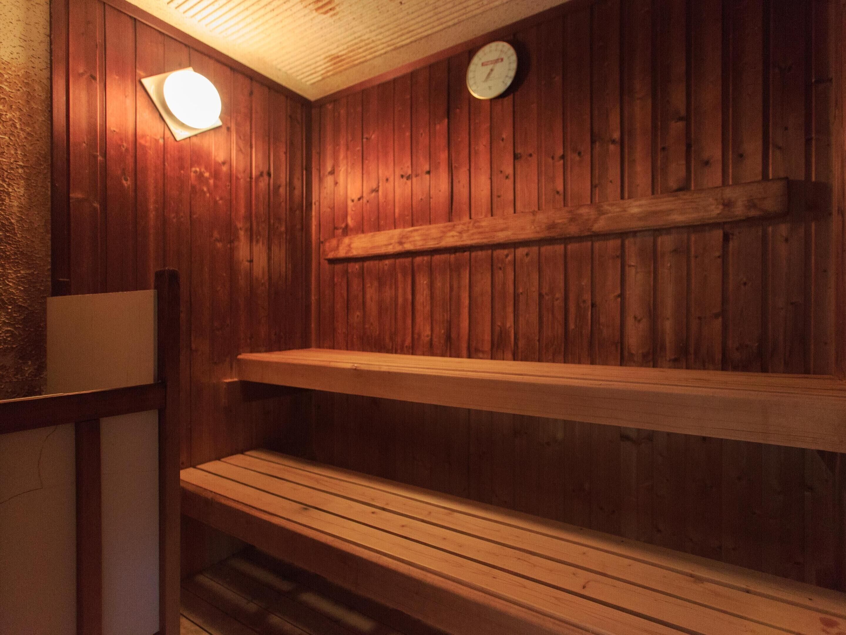 A wooden sauna with benches and a wall-mounted clock.