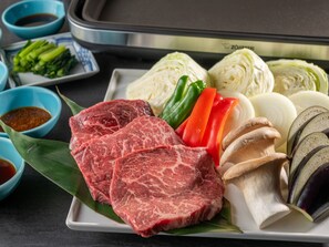 Um prato de carne bovina crua, vegetais e cogumelos sobre uma mesa.