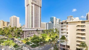 A high-rise building with multiple floors, surrounded by palm trees and other buildings. - @Marbella Lane - Stylish Island Stay w/ City Views (Honolulu)