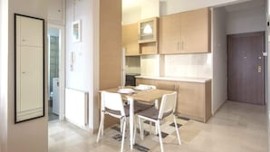 A compact kitchen with a dining table and chairs, wooden cabinets, and a visible door. - "Urban Comfort Stay" (Athina)