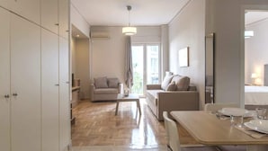 A modern, well-lit room with a dining table set for two, a sofa, and a chair. - "Urban Comfort Stay" (Athina)