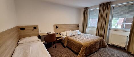 Ein Hotelzimmer mit zwei Einzelbetten, einem Schreibtisch und einem Stuhl.