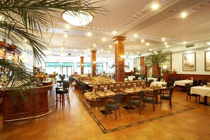 A spacious restaurant with high ceilings, ornate columns, and a variety of seating arrangements including booths and tables. - Hotel Avion (Prague)