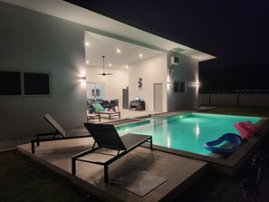 A modern outdoor pool area with a patio, lounge chairs, and a dining area. - Bauhinia house between sea and mountains. (Khuekkhak)