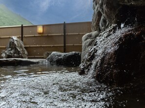 A hot spring area with large rocks, a wooden fence, and a mountain in the background. - Wan Wan Paradise Matsusaka (Matsusaka)
