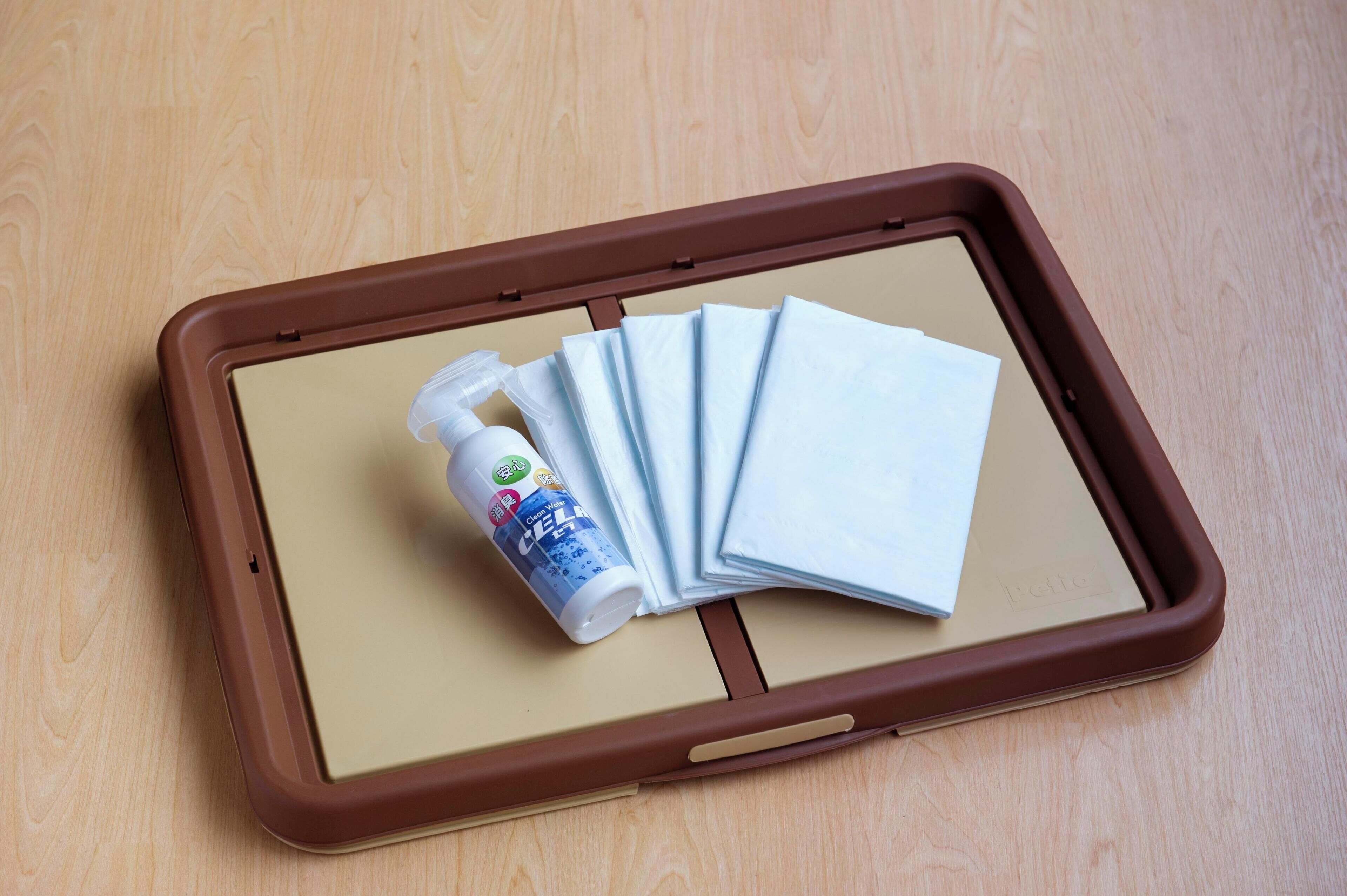 Una tableta con funda marrón, un frasco de gel hidroalcohólico y varias mascarillas sobre una superficie de madera.