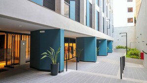 A modern hotel corridor with a glass entrance, potted plants, and a tiled floor. - w* | Engaging 2BR w/ balcony in Miraflores (Lima)