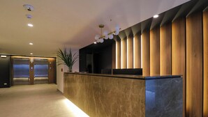 A modern reception area with a marble counter, wooden paneling, and a ceiling light fixture. - w* | Engaging 2BR w/ balcony in Miraflores (Lima)