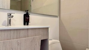 Et badeværelse med en hvid vask, et spejl og et toilet.