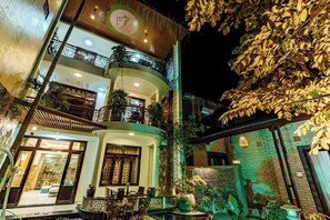 A multi-story building with balconies, indoor plants, and a well-lit entrance. - Nana House Homestay (Hue)
