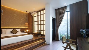 A modern bedroom with a bed, a wooden desk, a chair, and a view of the outdoors. - Nana House Homestay (Hue)