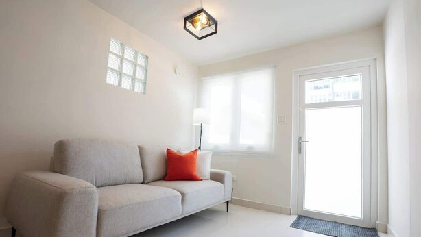 A modern living room with a sofa, a door, and a window. - New 1Bedroom Apt. In Condado! C.4 (San Juan)