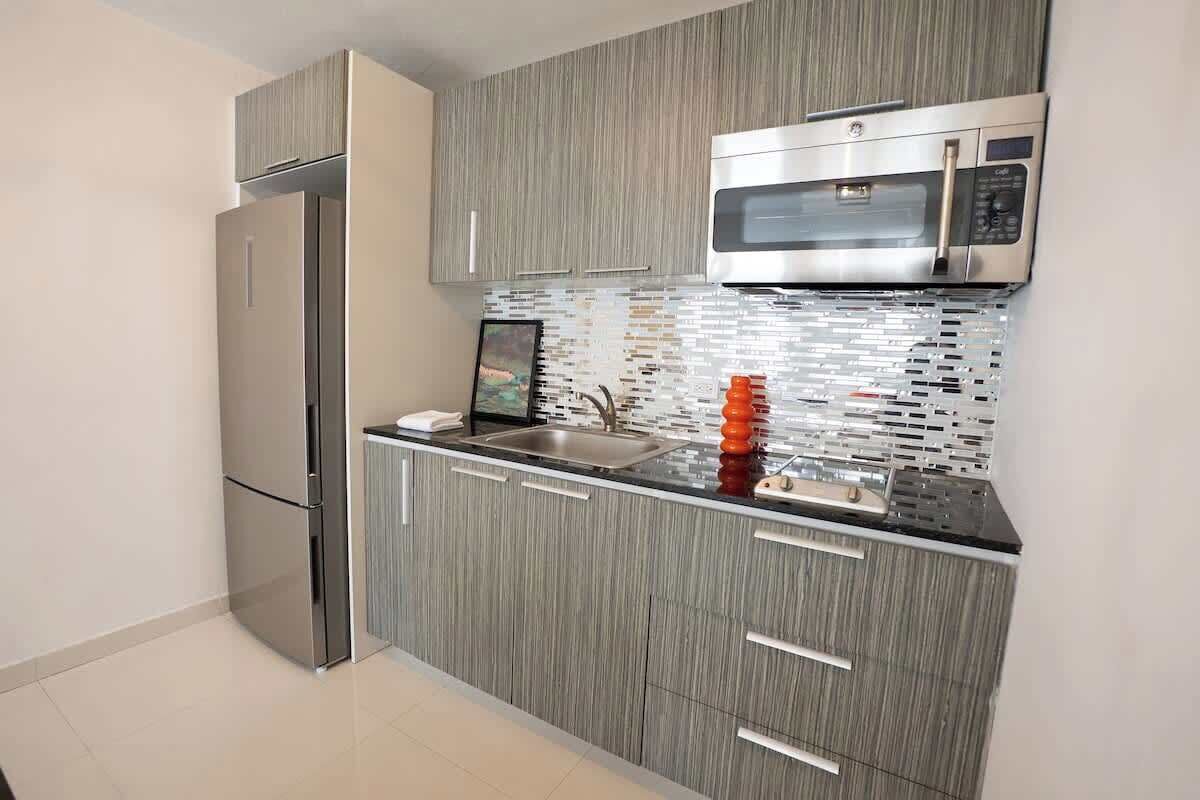 Una cocina moderna con un refrigerador de acero inoxidable, un microondas y un salpicadero de azulejos.