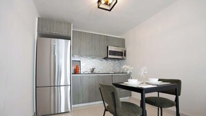 A modern kitchen with a stainless steel refrigerator, a microwave, and a dining area with two chairs and a table set for two. - New 1Bedroom Apt. In Condado! C.4 (San Juan)