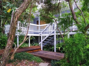 A wooden deck with a white railing, surrounded by lush greenery and trees.