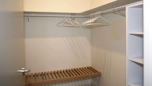 Un armario con estantes de madera y perchas metálicas.