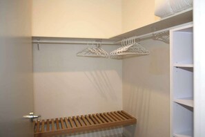 Un armario con estantes de madera y perchas metálicas.