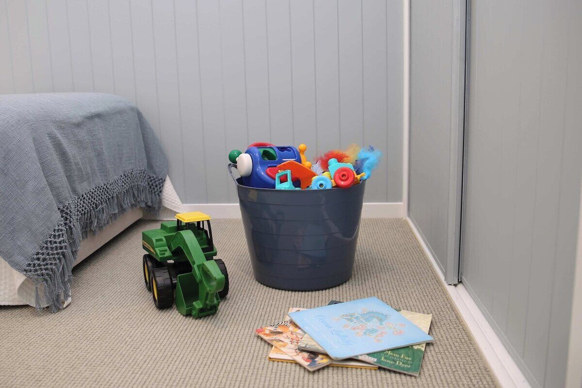 Un espace de jeux pour enfants avec des jouets, un tracteur et des livres éparpillés sur le sol.
