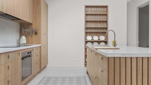 Una cocina moderna con armarios de madera, horno empotrado e isla central con lavamanos.