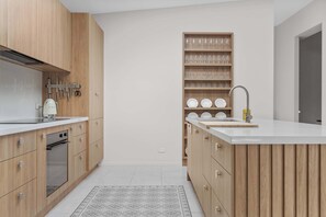 Una cocina moderna con armarios de madera, horno empotrado e isla central con lavamanos.