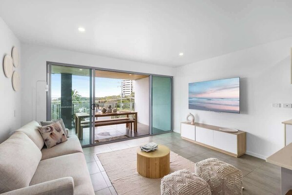 A modern living room with a sofa, a coffee table, and a TV mounted on the wall.