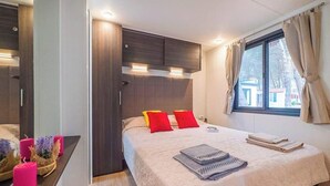 Une chambre à coucher moderne avec un lit, une table de chevet et une fenêtre avec des rideaux.