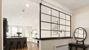 Una cocina moderna con una isla central, taburetes de bar, un radiador y un ventanal con diseño de cuadrícula.