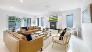 Ein geräumiges Wohnzimmer mit Kamin, Ledersofas und Korbsesseln.