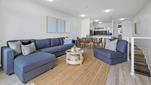 A modern living room with a grey sectional sofa, a coffee table, and a staircase leading to an upper level.